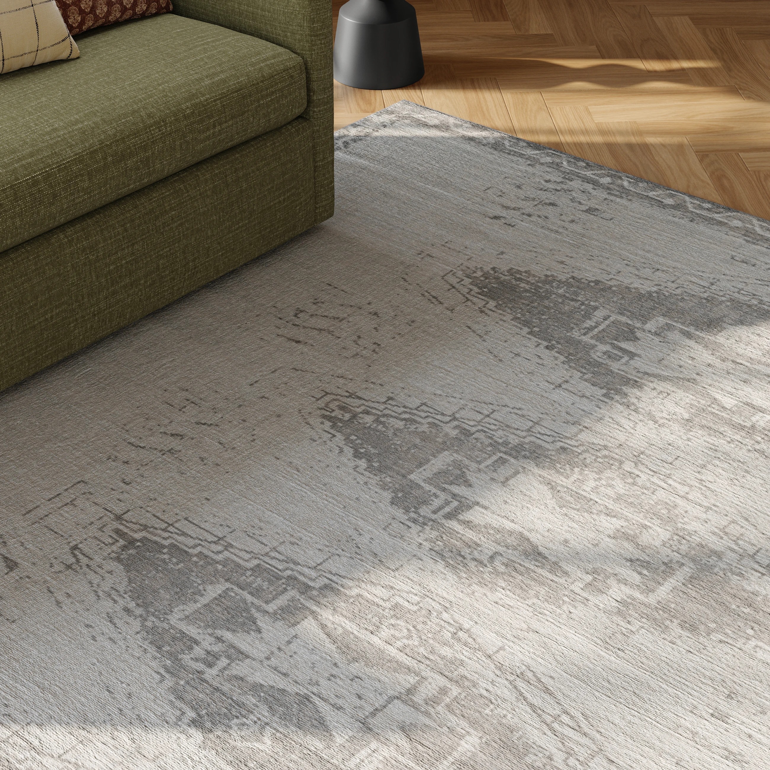A living room rug with geometric patterns on a wooden floor next to a green sofa and a round black side table