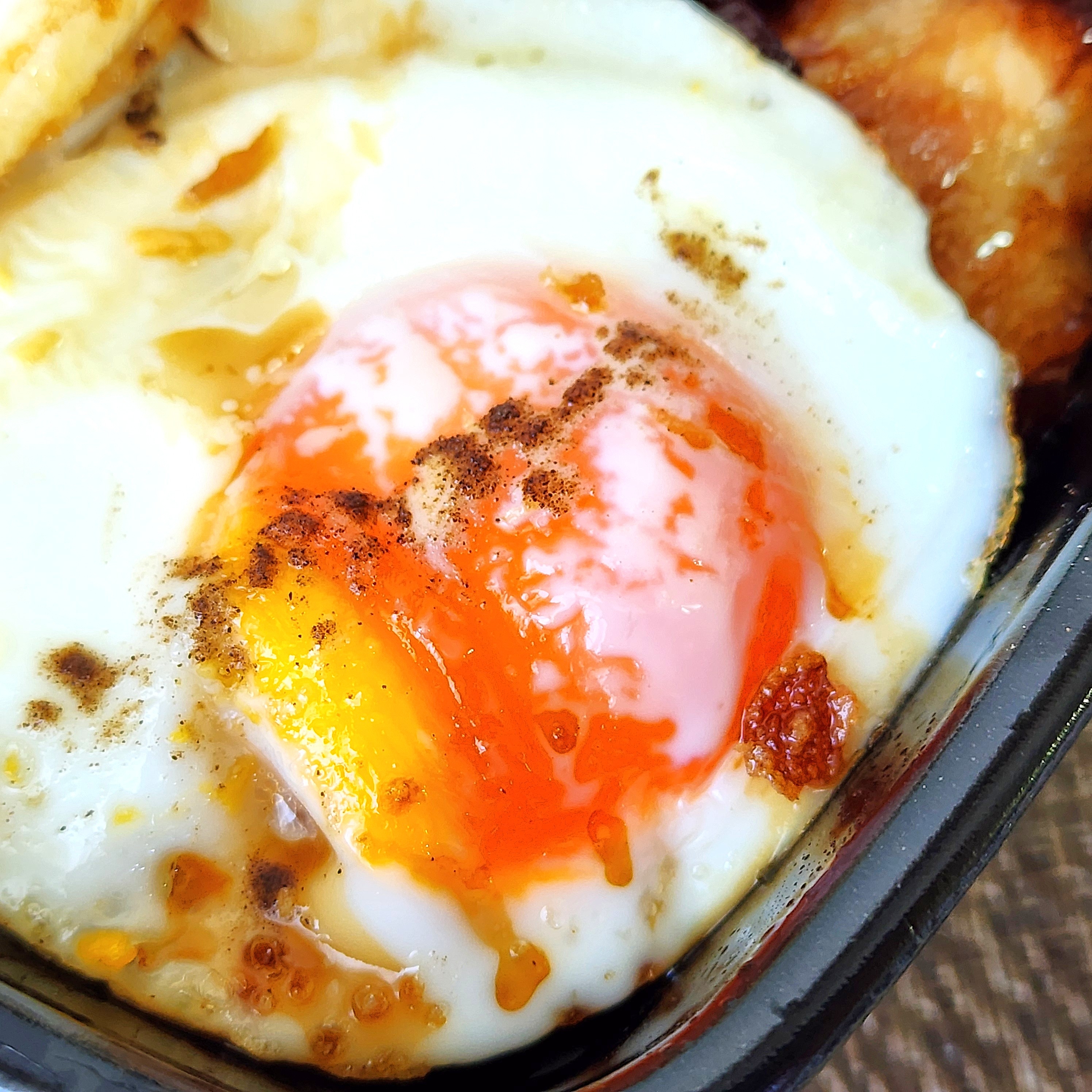 半熟の目玉焼きが焼かれている様子。上には香ばしい焦げ目が付いており、食欲をそそる朝食の一部です。
