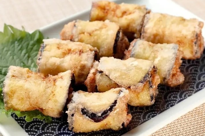 皿に盛られた揚げた茄子の巻き寿司。シソの葉が添えられている。