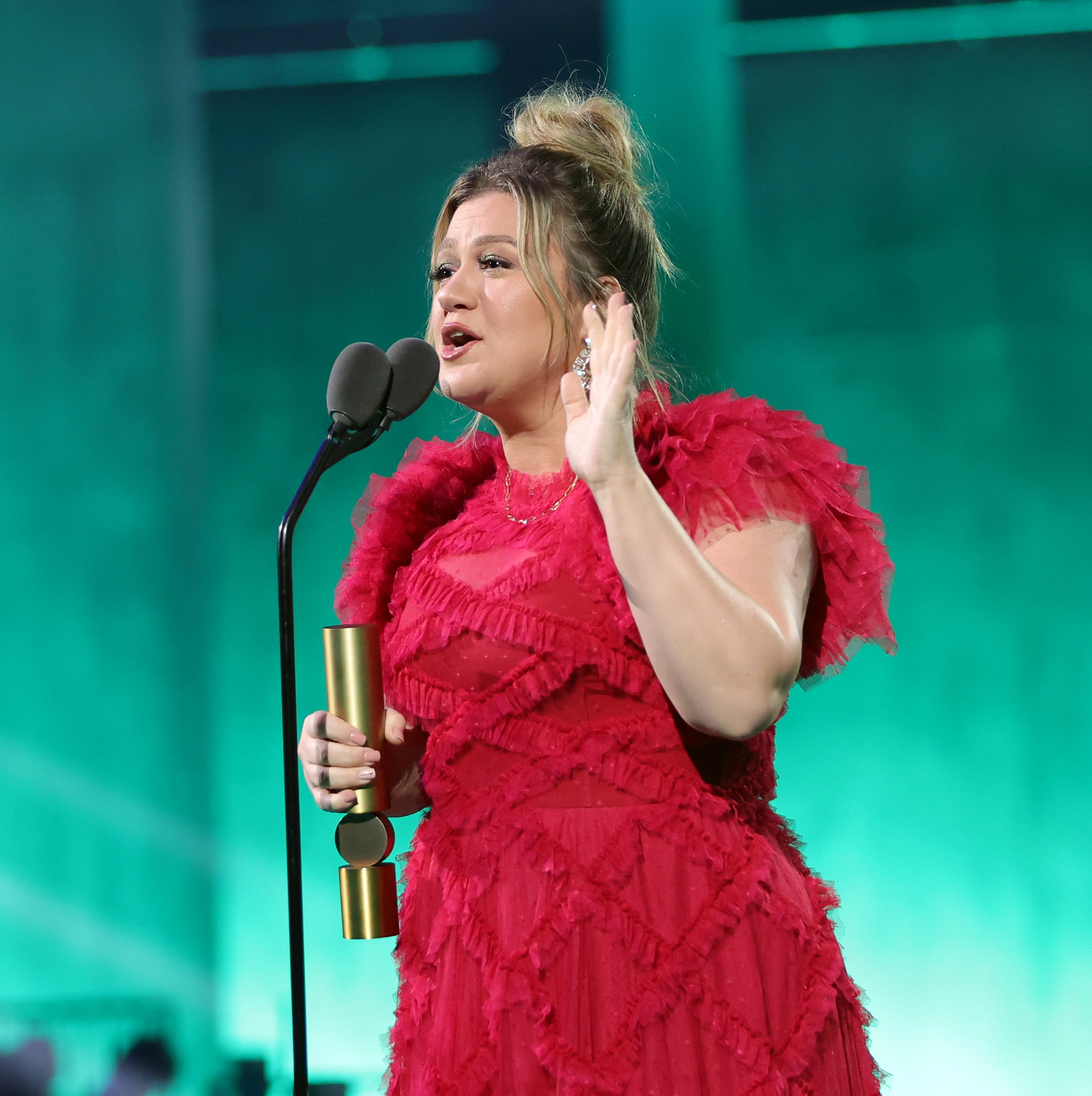 Kelly Clarkson speaking into a microphone at a 2022 event