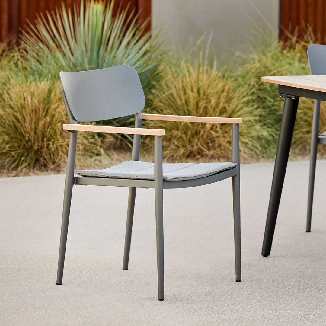 Modern outdoor chair with wooden armrests and sleek design, positioned on a patio