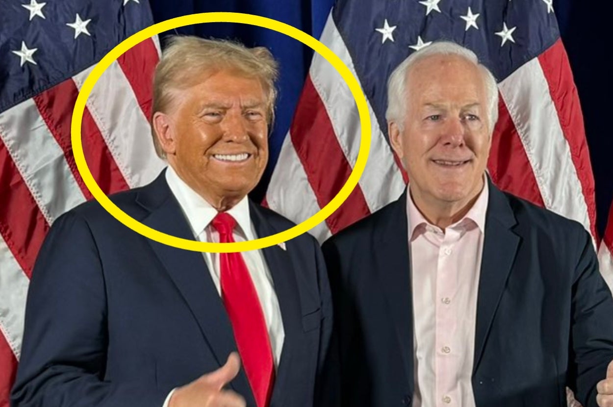 Two men smiling in front of American flags. The man on the left is circled. They are dressed in formal suits