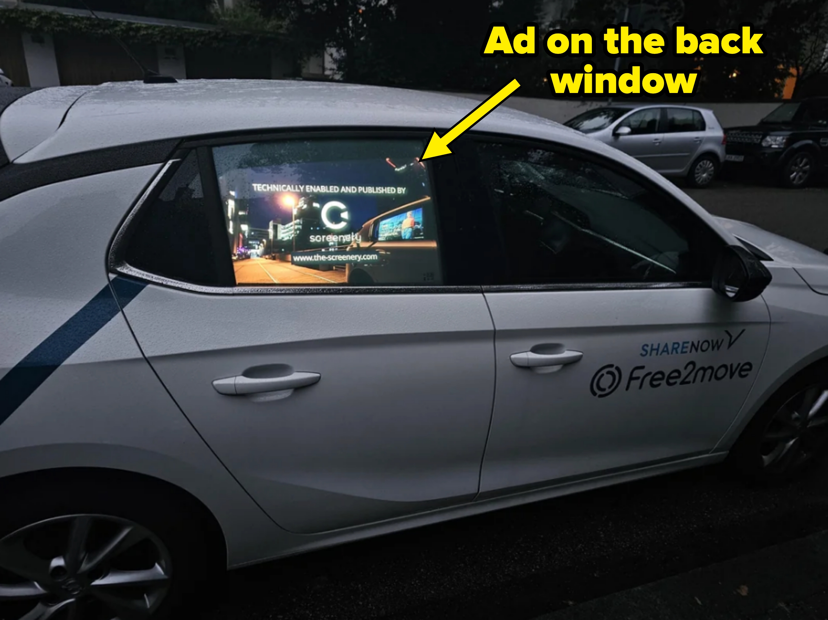 Car's back window displays an electronic screen showing an ad