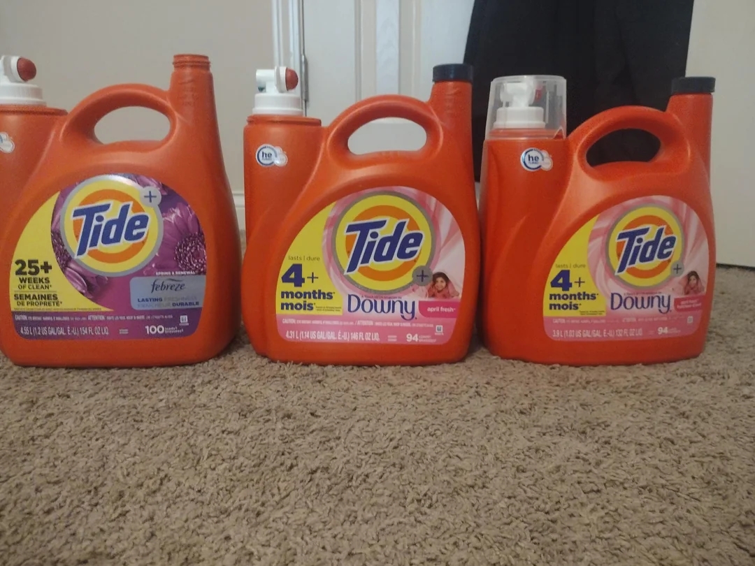 Three large Tide detergent bottles on carpet, labeled for various uses, including Febreze freshness and Downy softness