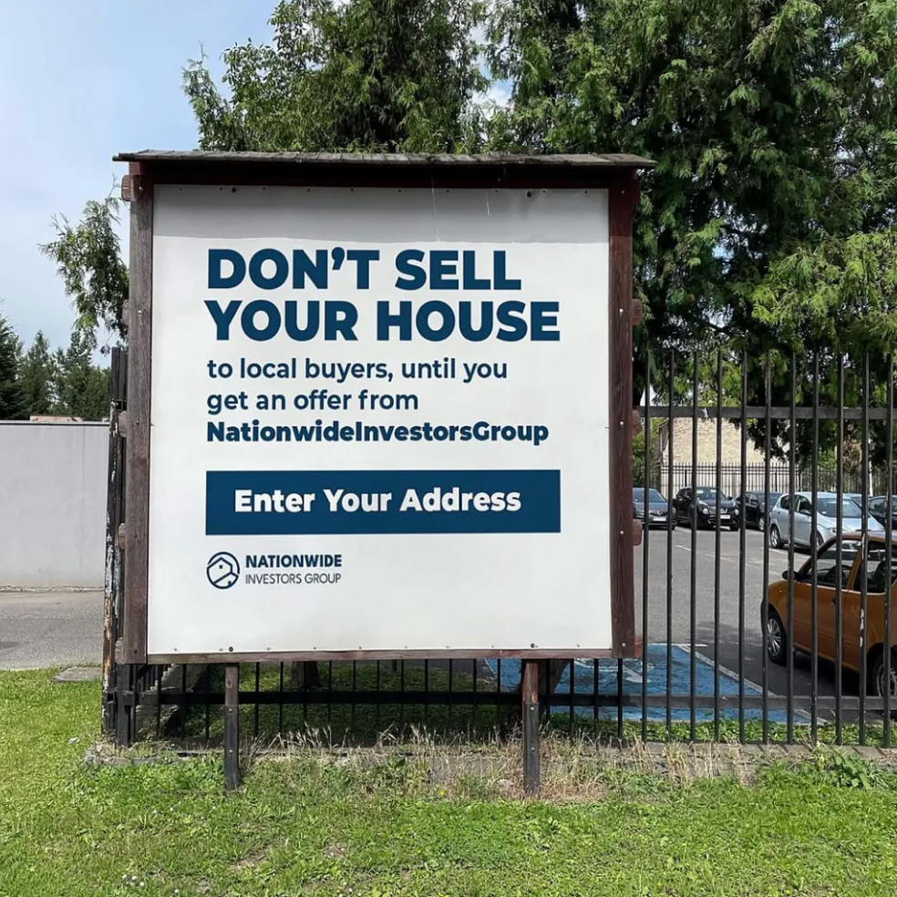 Sign reads: "DON’T SELL YOUR HOUSE to local buyers, until you get an offer from NationwideInvestorsGroup"