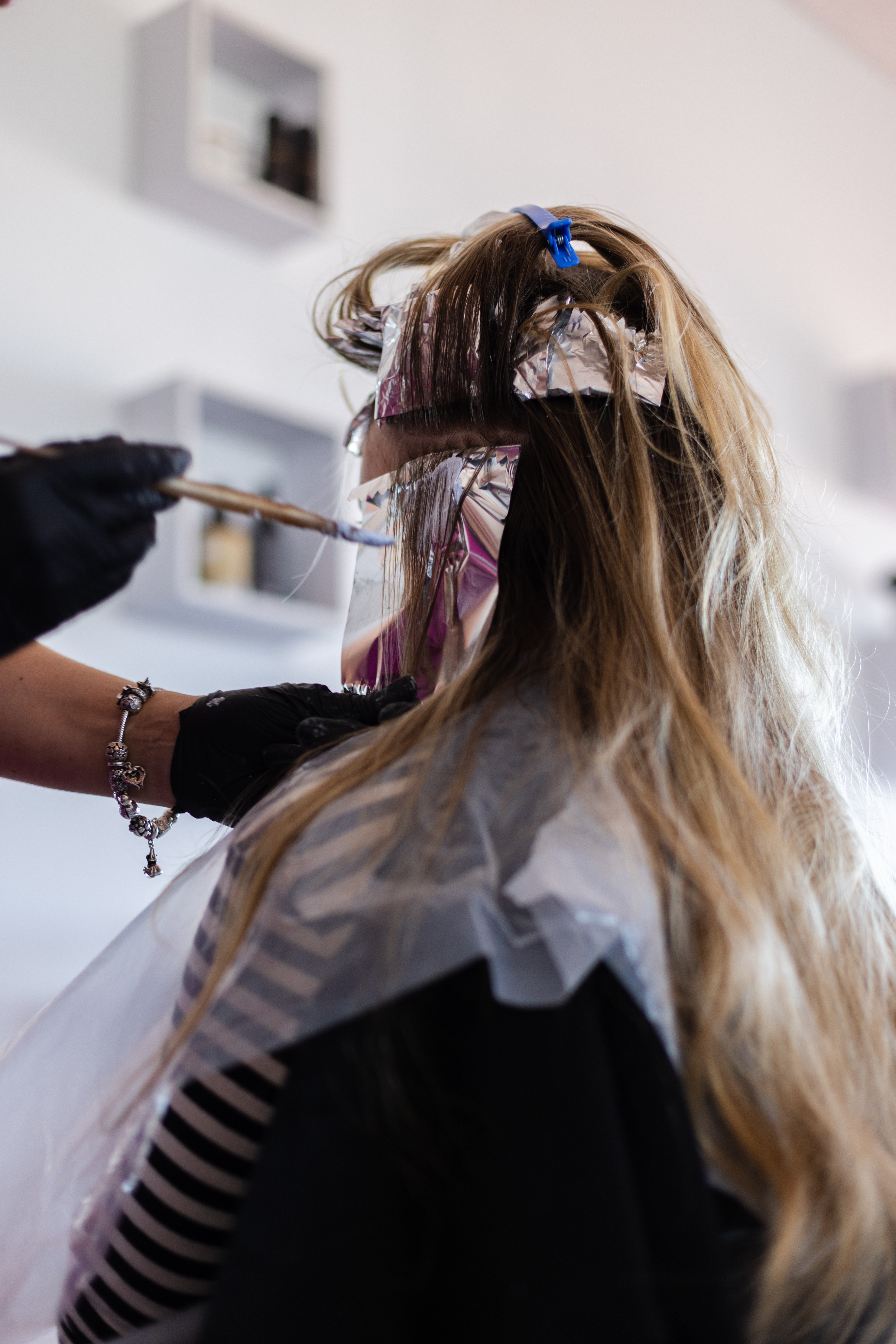 Hairdresser applying highlights to a client's hair using foils in a salonchair, focusing on the highlighting process