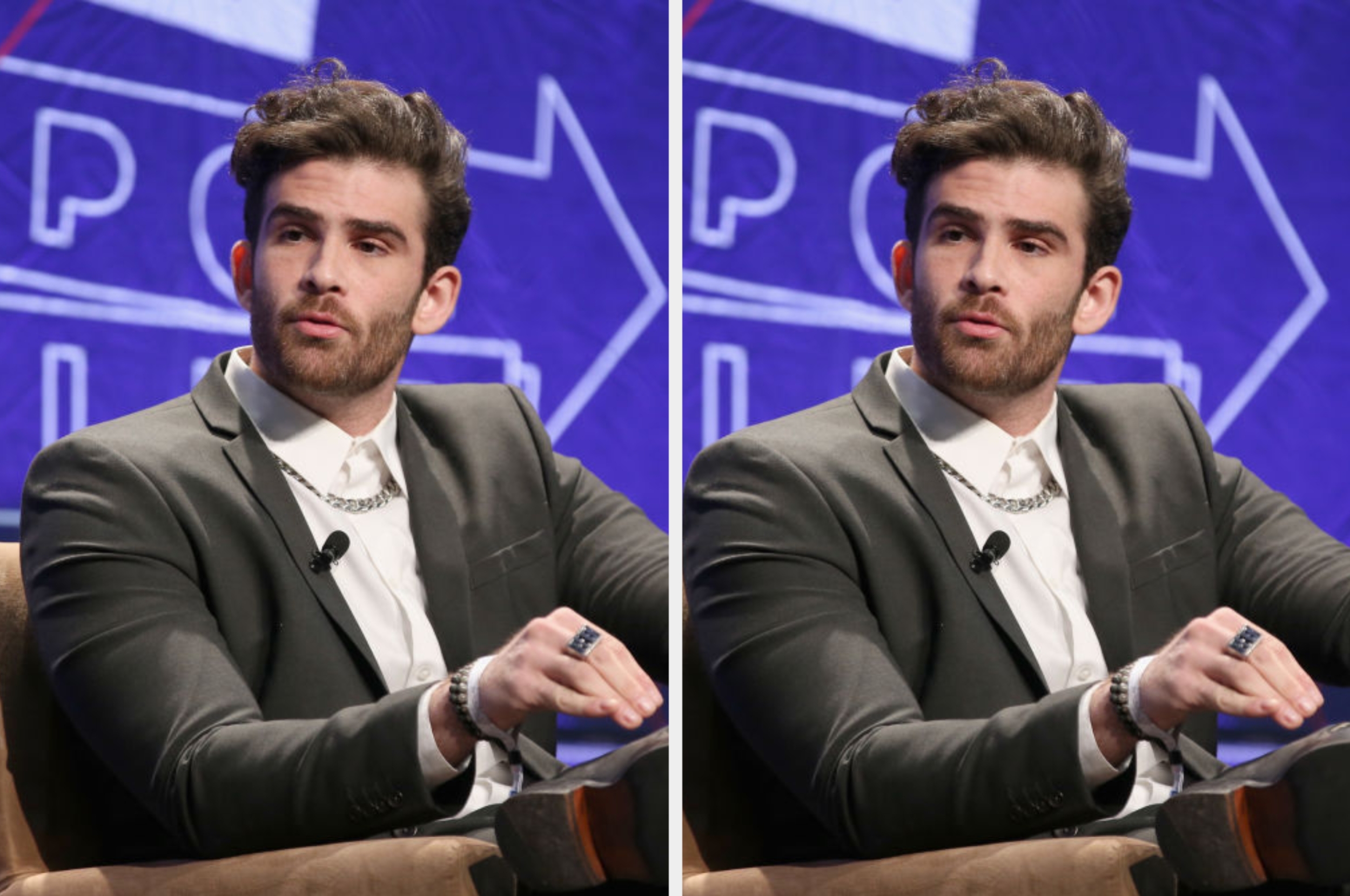 A man in a suit speaks at a public event, gesturing with his hand