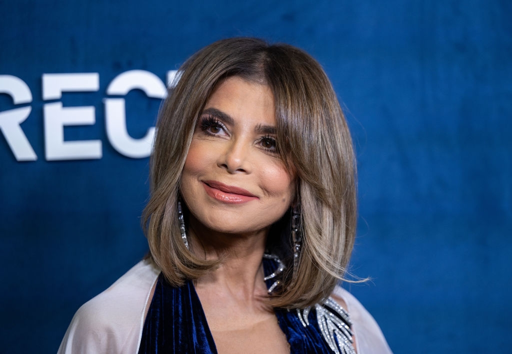 Person with shoulder-length hair in a formal outfit, smiling at an event