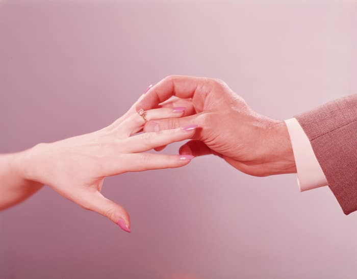 Hands exchanging a ring, symbolizing engagement or marriage, against a soft background