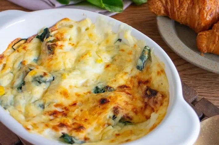 グラタンとクロワッサンが並んでいるテーブル。食欲をそそる焼き色が付いた料理。