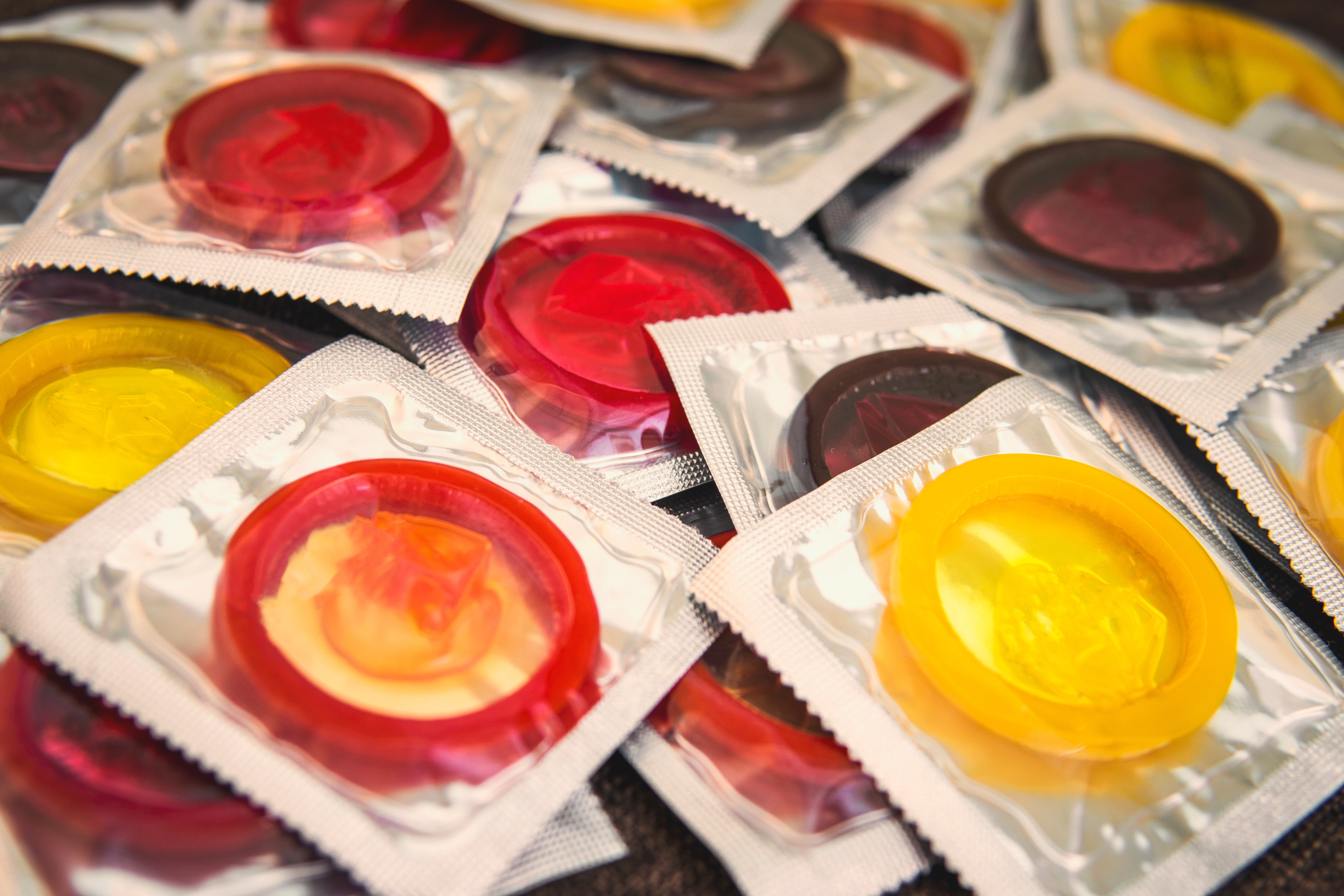 Packets of various colored condoms scattered in a pile
