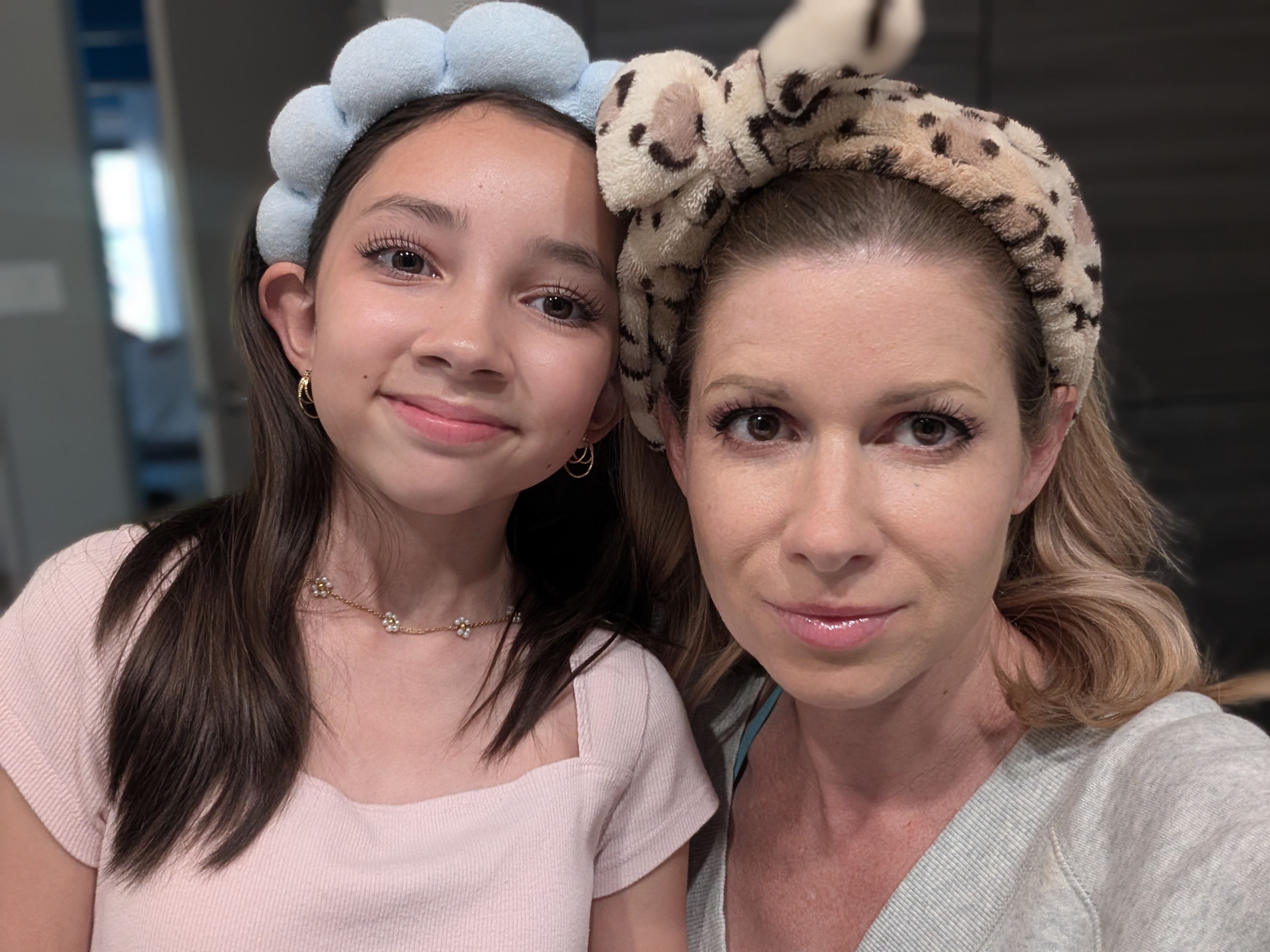 Two people wearing headbands, posing together and smiling indoors.
