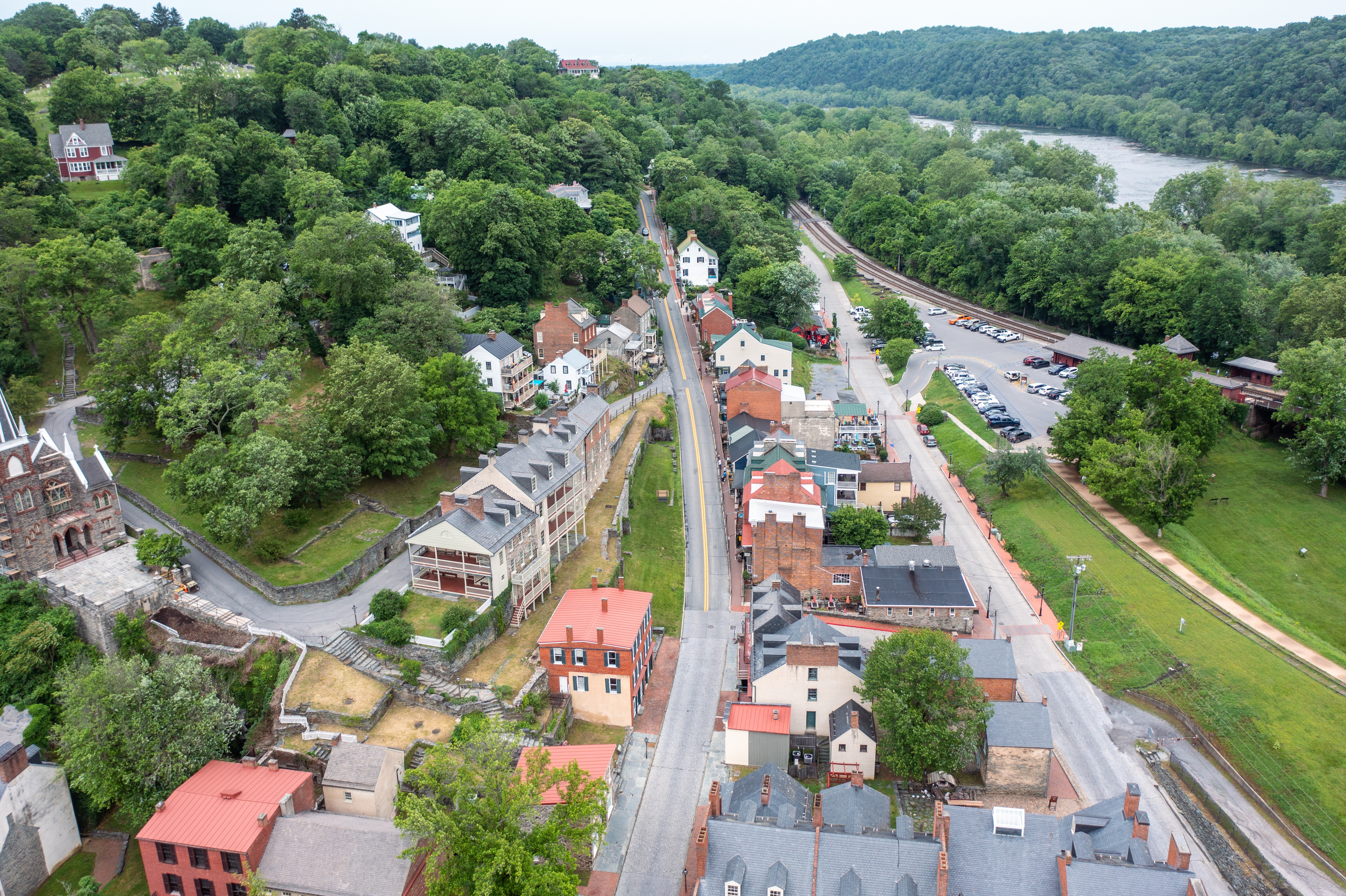 Aerial view of a historic town nestled among lush green trees, with a river visible in the background