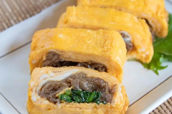 皿に盛られた数切れの卵で包まれた肉巻きの料理。