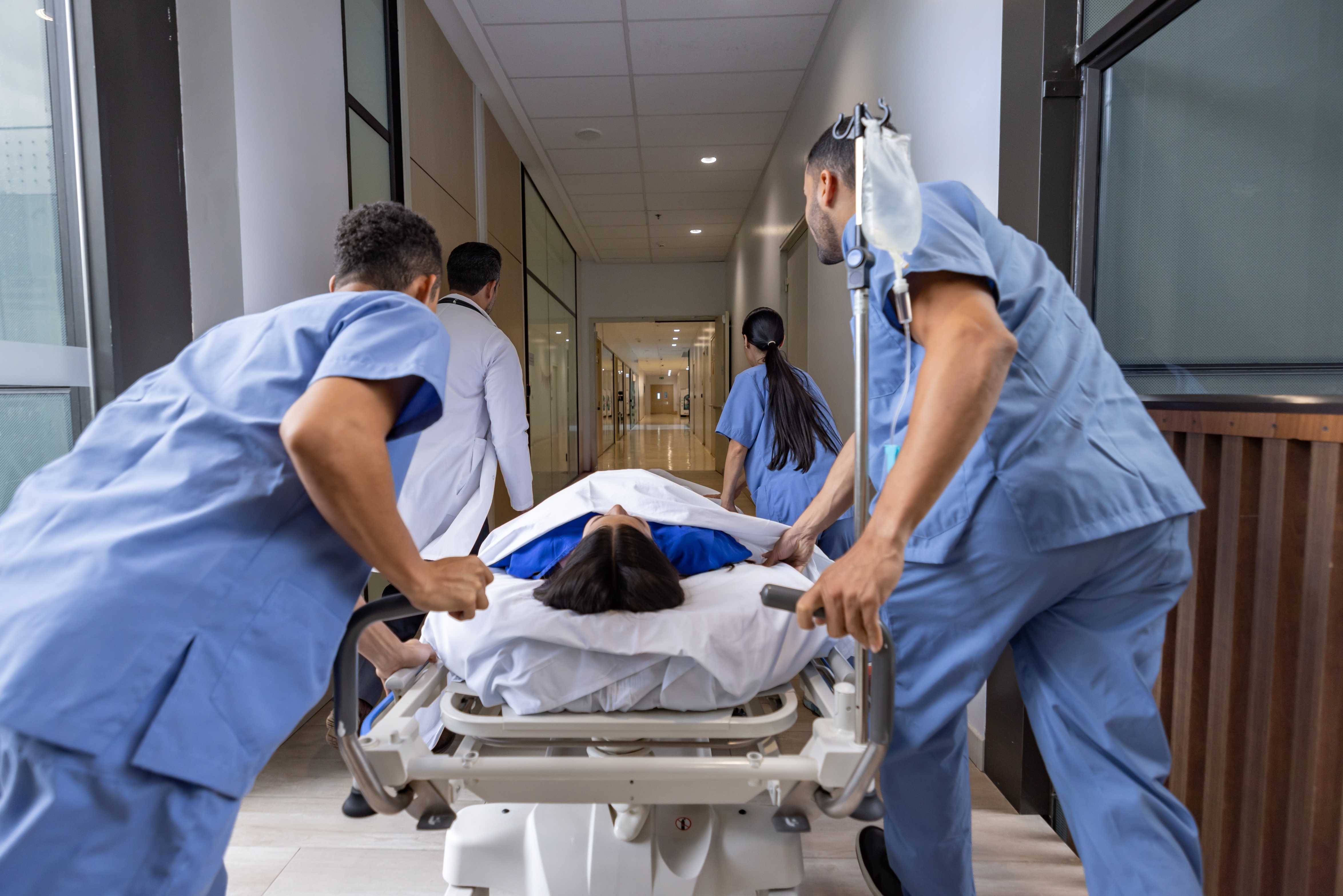 Medical team rushing a patient on a stretcher through a hospital corridor, conveying urgency and teamwork in a healthcare setting