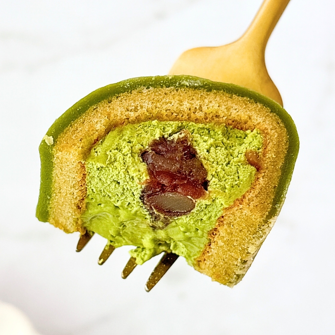 フォークで持ち上げられた、抹茶クリームとあんこが層になったデザート。