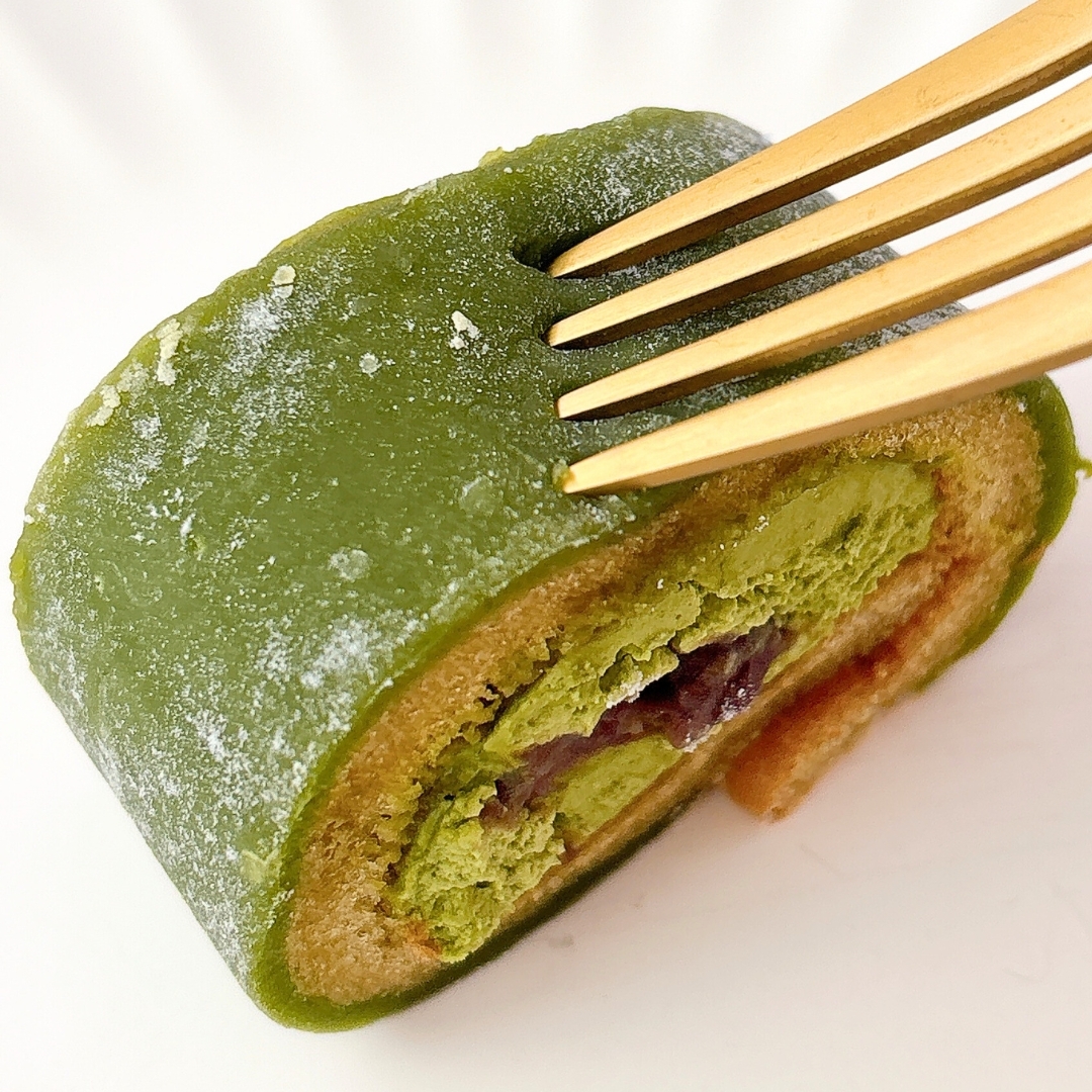 フォークで一口サイズに切った抹茶ロールケーキ。クリームと果物が見える。