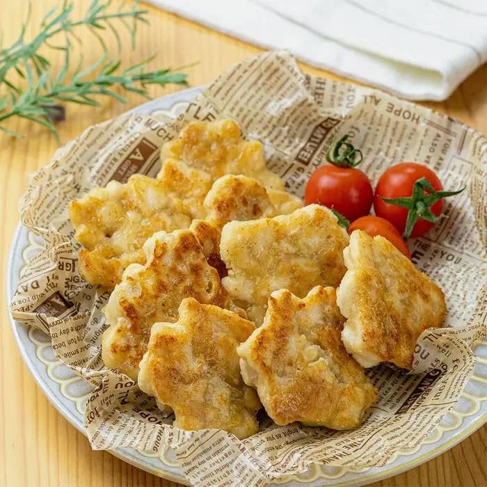 新聞紙の上に盛られた唐揚げ風の料理とサクランボトマトの盛り合わせ。