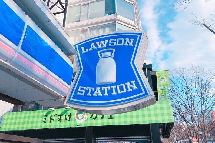 ローソンステーションの看板が街中に掲示されている風景。マンションと他店舗が背景にあり、冬の空が広がっています。