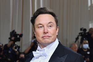 タキシードを着た男性がカメラを見てポーズ。背景にカメラマンたち。