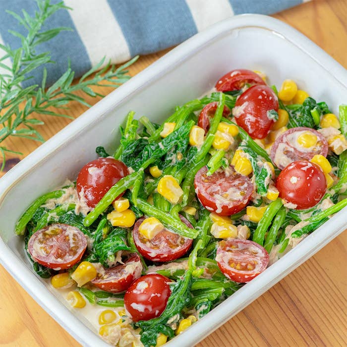 皿に盛られたサラダ。トマト、コーン、緑の野菜がクリーミーなドレッシングで和えられています。