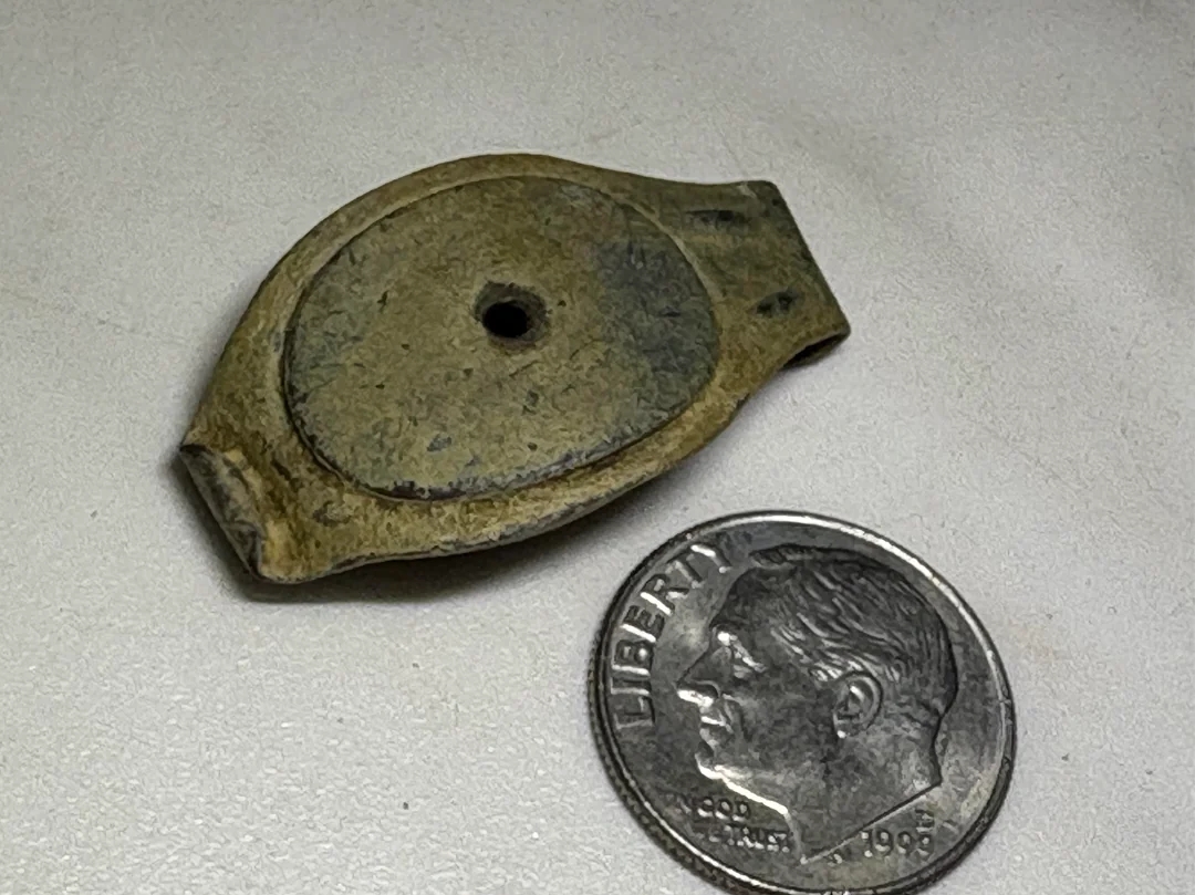 Stone artifact with a hole in the center next to a U.S. dime for scale comparison