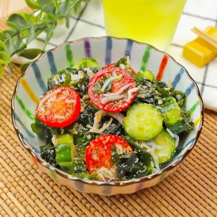 トマト、キュウリ、海藻を使ったサラダがボウルに盛られている。背景に飲み物がある。