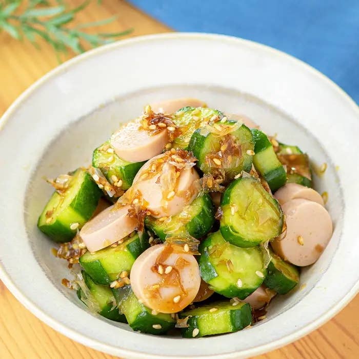 きゅうりとソーセージがごま油風味のソースで和えられたサラダが白い皿に盛り付けられている。