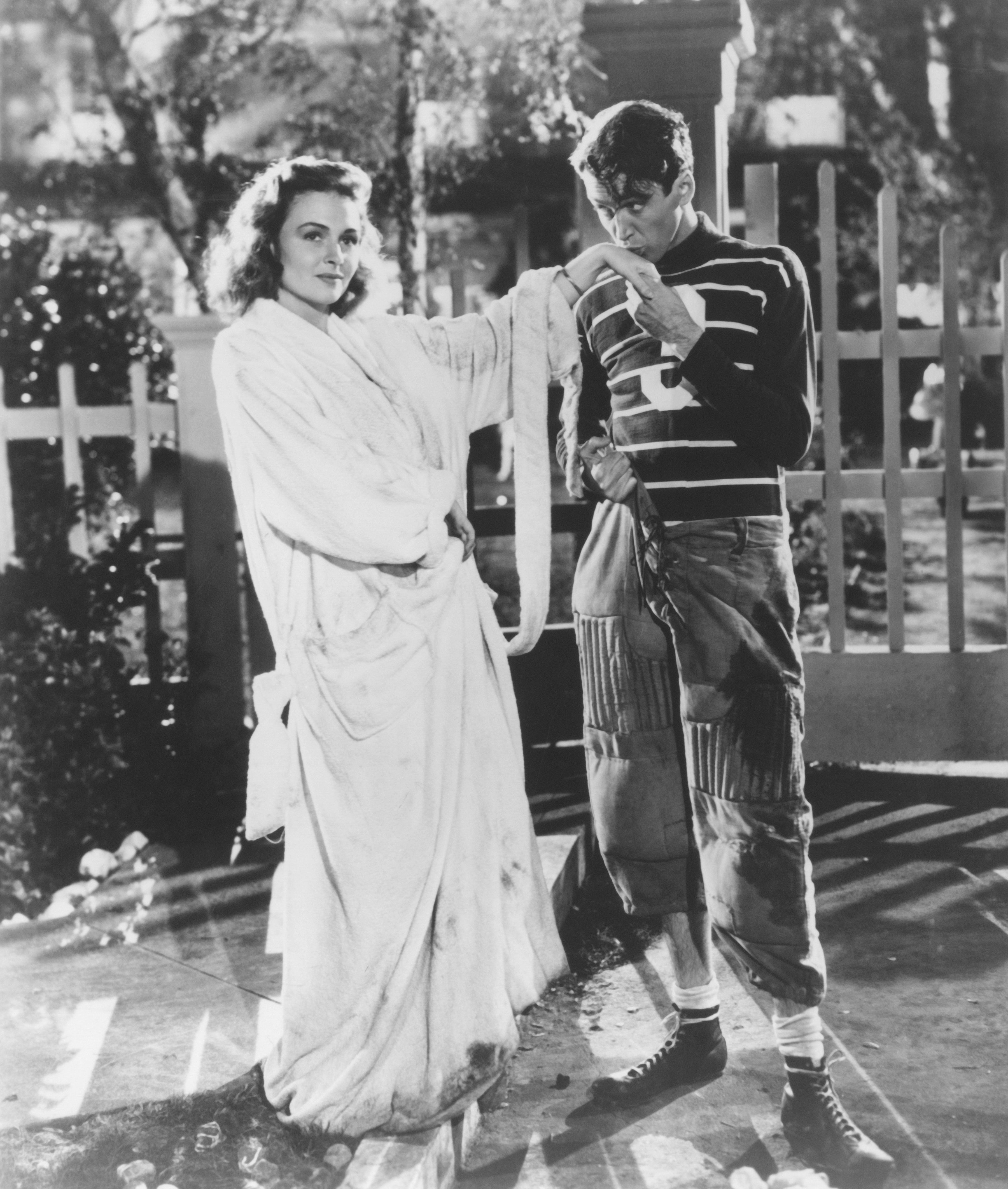 Vintage scene with a woman in a flowing dress and a man in a striped shirt and patched pants, engaged in playful interaction on a set