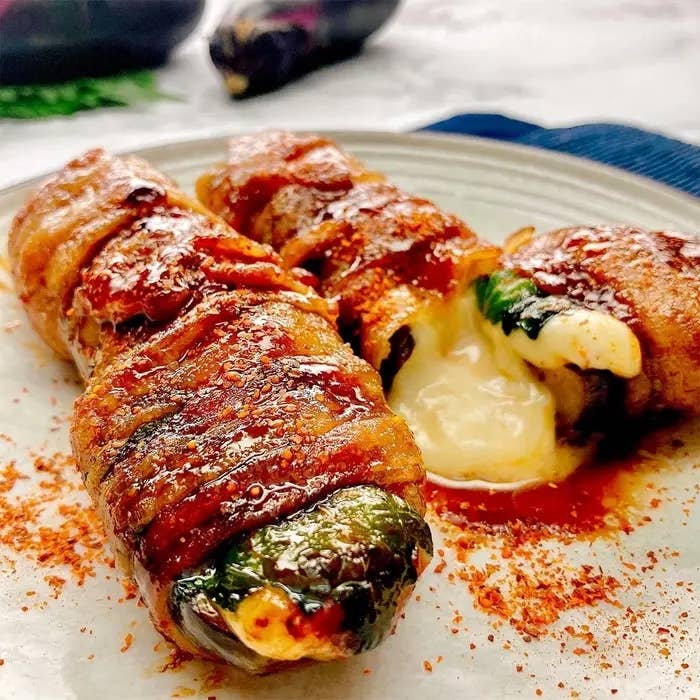 豚肉で巻いたなすの中から、とろりとしたチーズがはみ出している料理が皿に載っている。