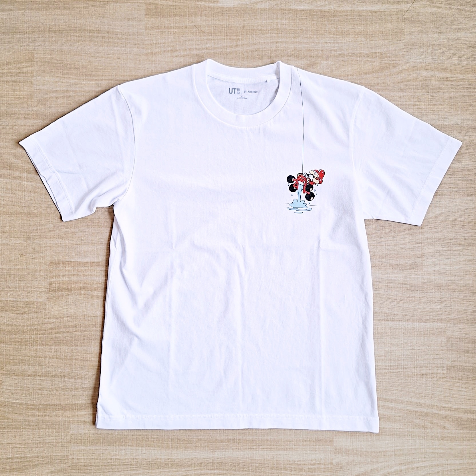 白いTシャツにキャラクターの小さなプリントが施されています。