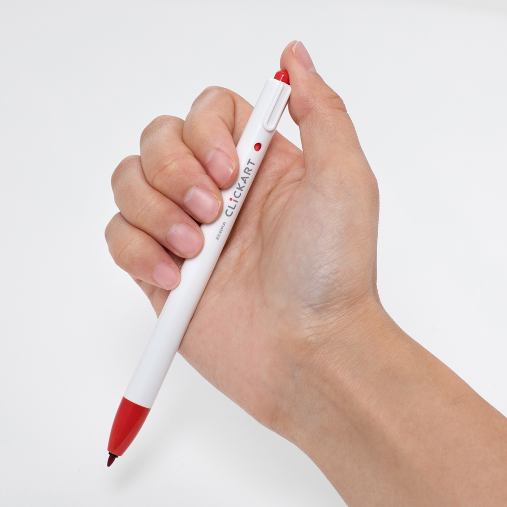 手に持った赤と白のボールペン。ペンクリップに「CLICK ART」の文字が見える。