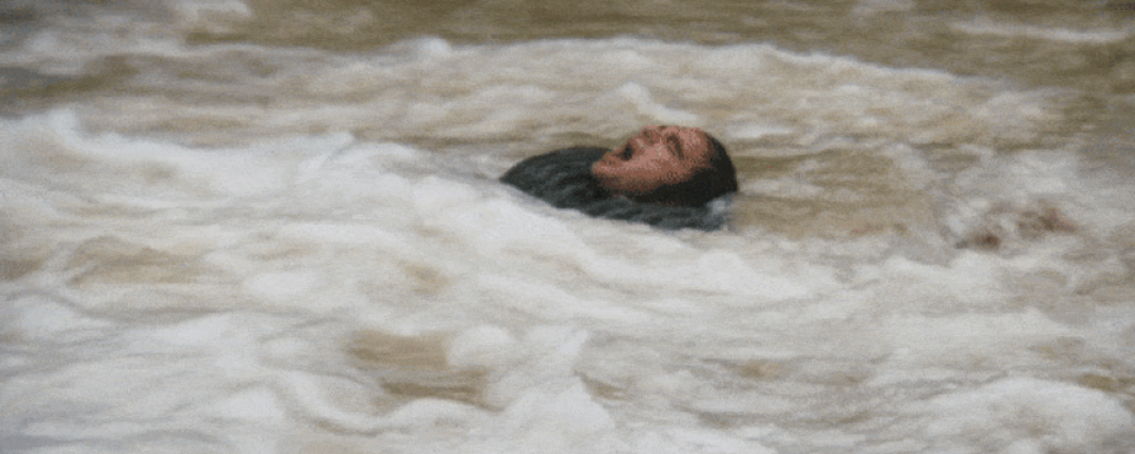 Person struggling in turbulent water, mouth open in distress