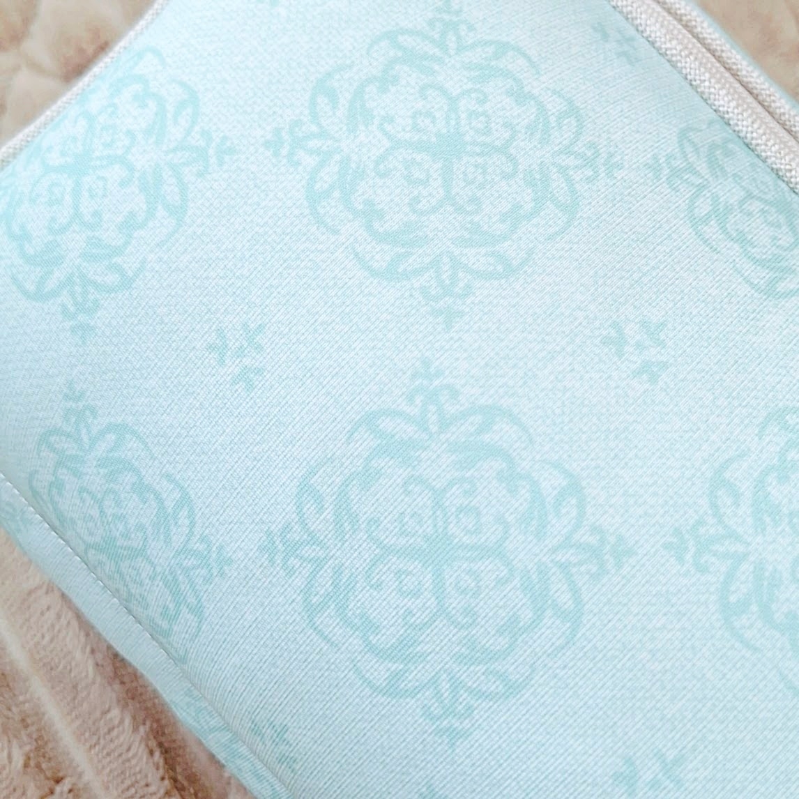 装飾的なパターンが施されたクッションがベージュの表面に置かれています。