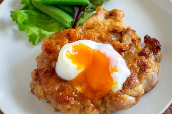 鶏肉の上に半熟の卵がのった料理。横にはレタスとインゲンの添え物。