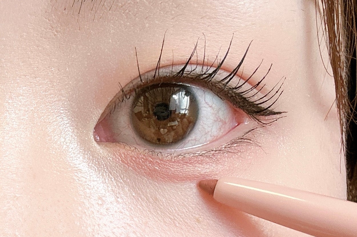 まつげメイクされた目に、ピンクのアイライナーを使っている様子。