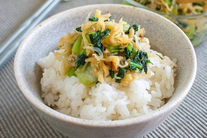 白米の上に野菜と具材が乗った和風丼。背景に似た料理がガラスの器に盛られている。