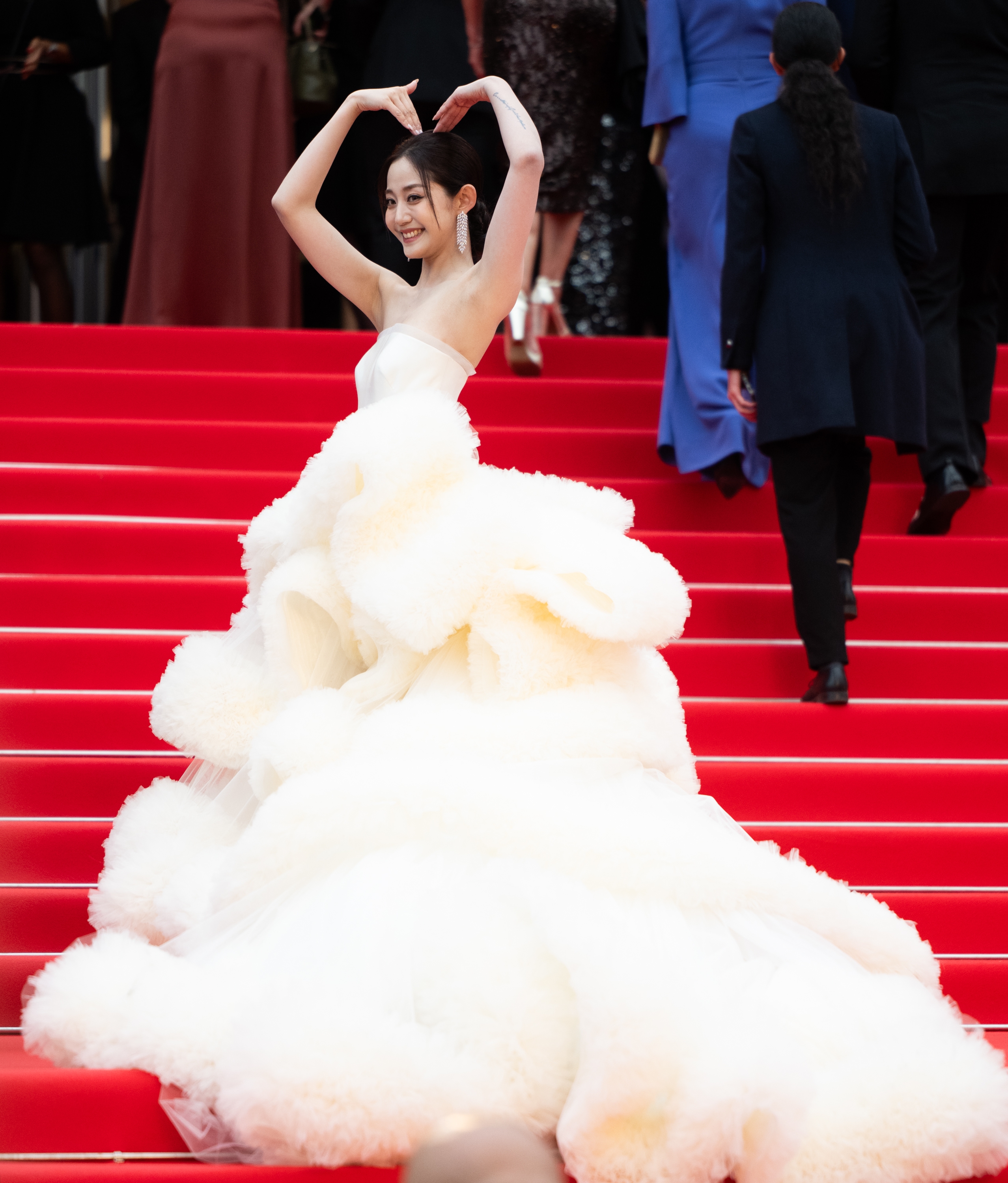 Wan QianHui in a glamorous, voluminous gown posing on red carpet stairs