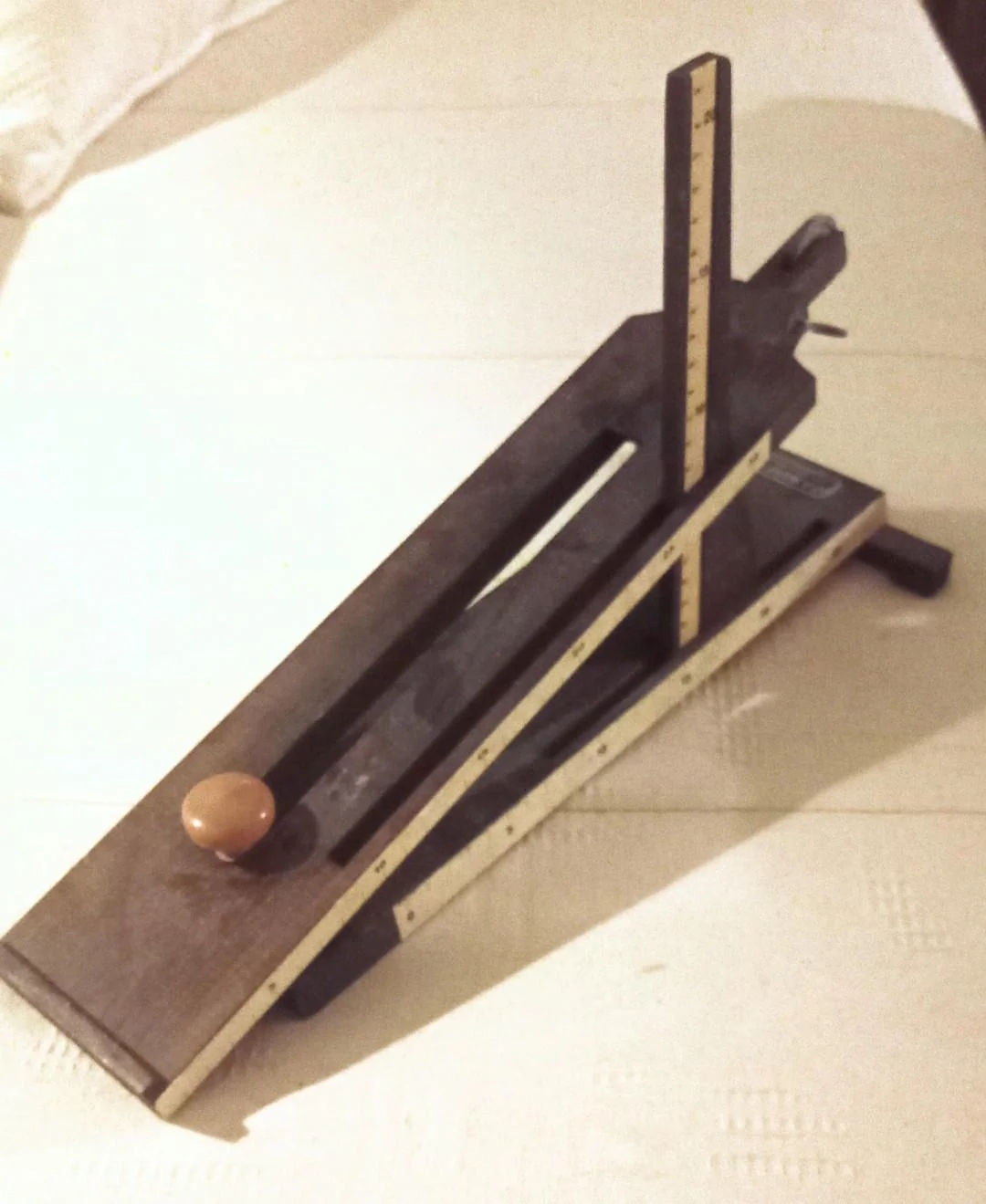 Wooden Rube Goldberg-style machine with a ball, featuring a sloped track and a vertical measurement scale