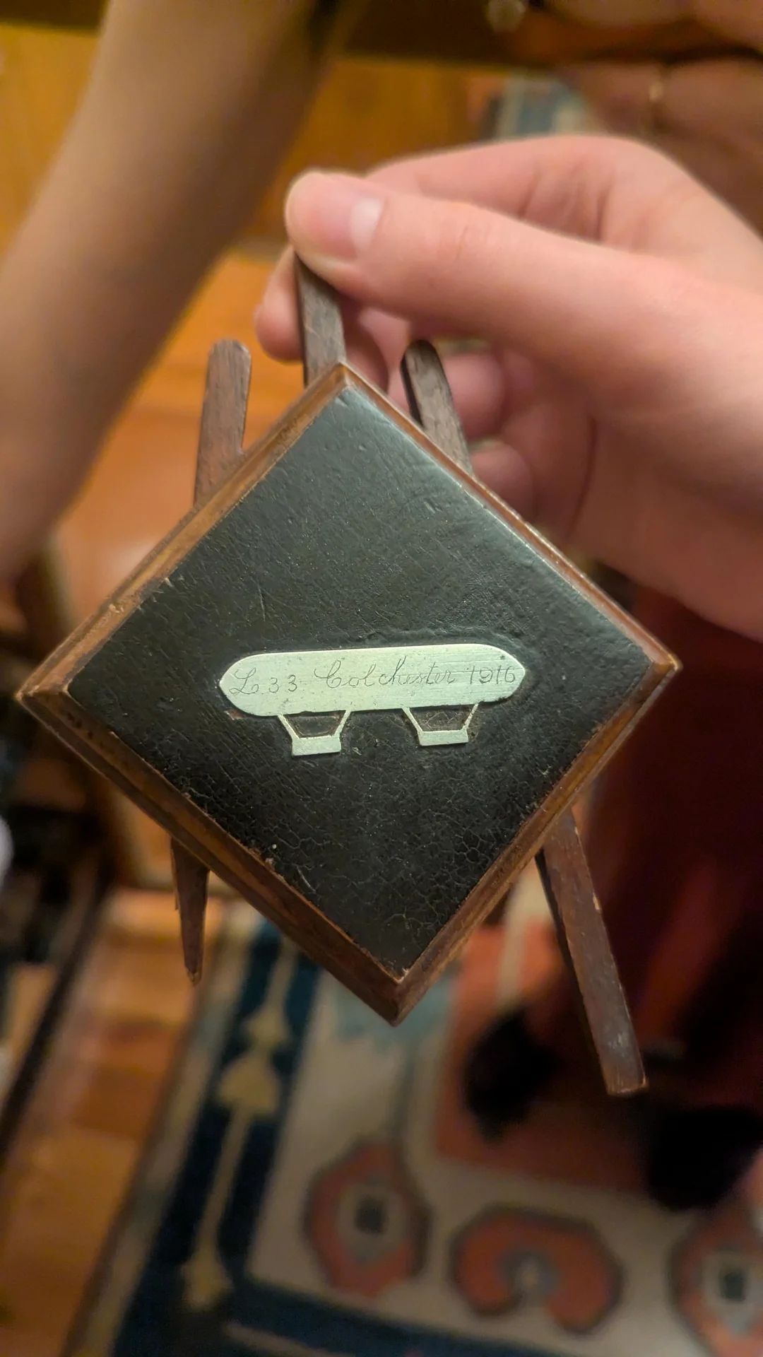 Close-up of hands holding a vintage stereoscope slide with the engraving "E.S. Co. London 1916."