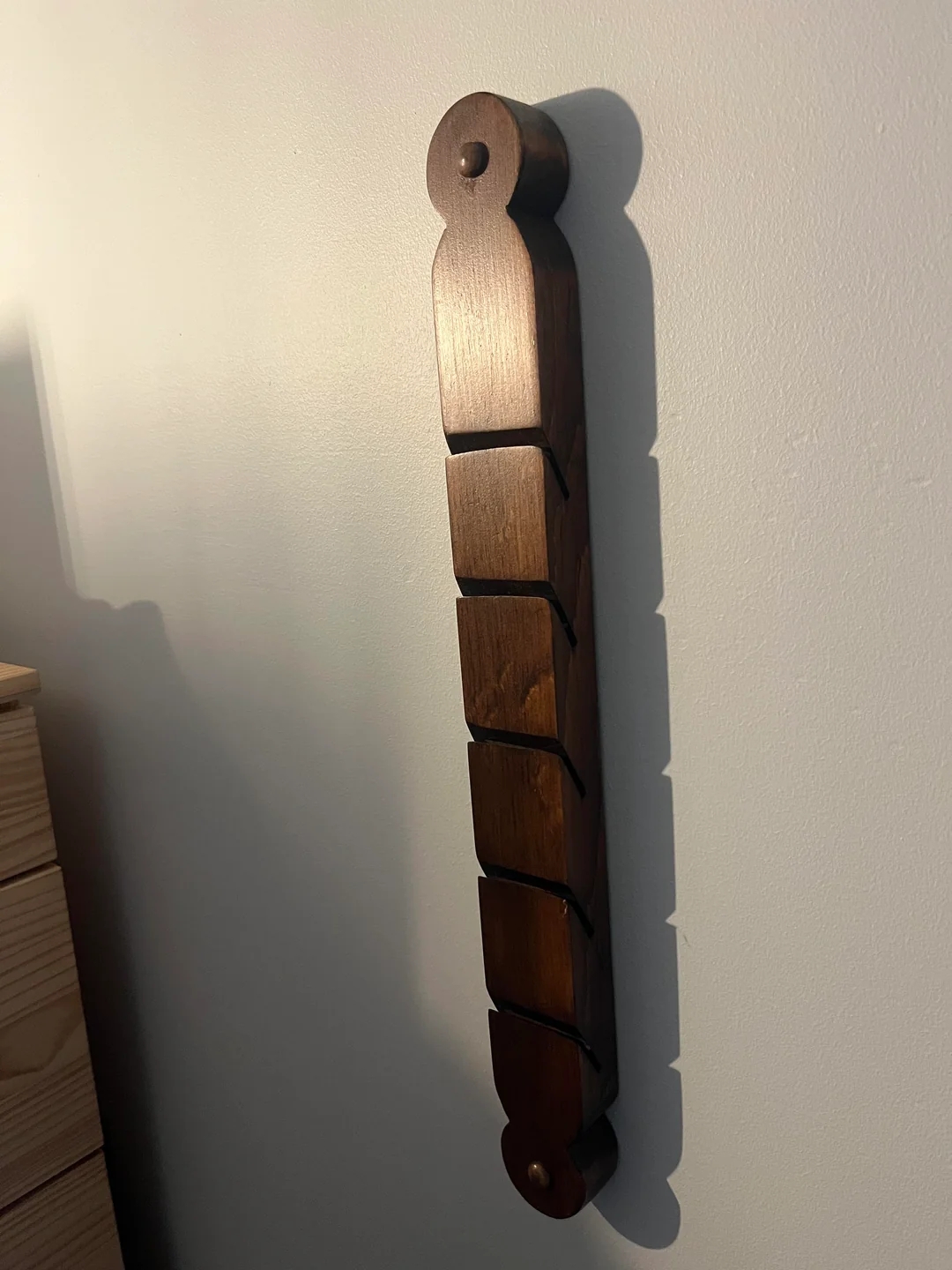 Wooden coat rack with curved hooks, mounted vertically on a wall