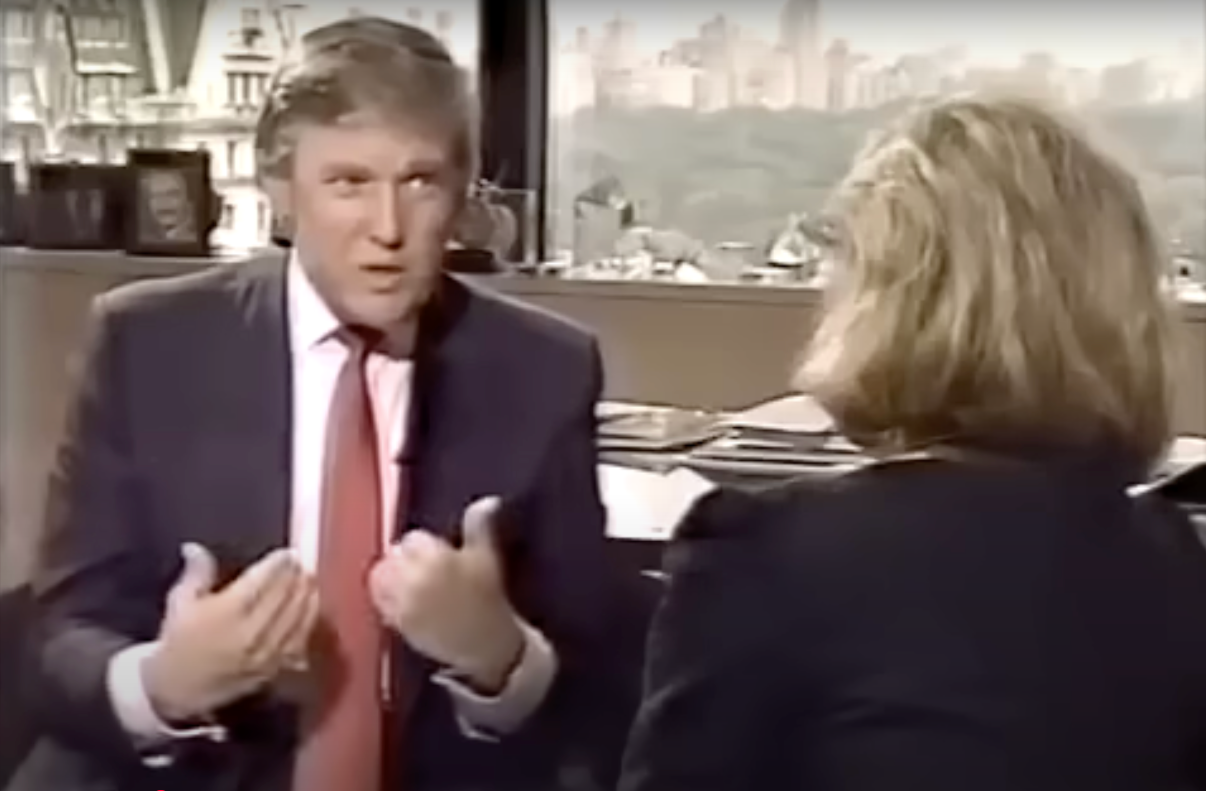 Two people having a conversation in an office setting with a city view in the background