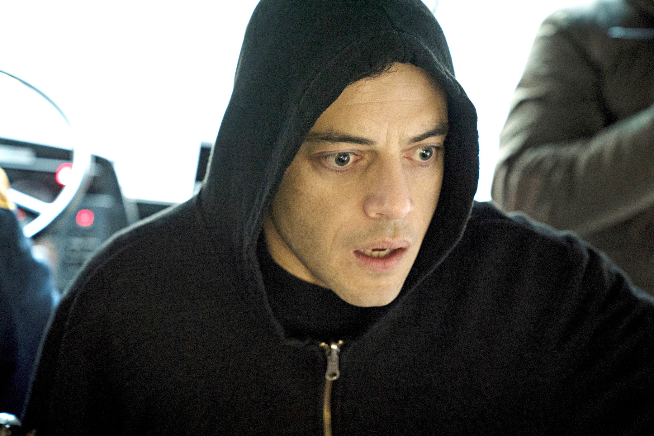 A person wearing a hooded jacket looks intensely focused, appearing in a TV or movie scene