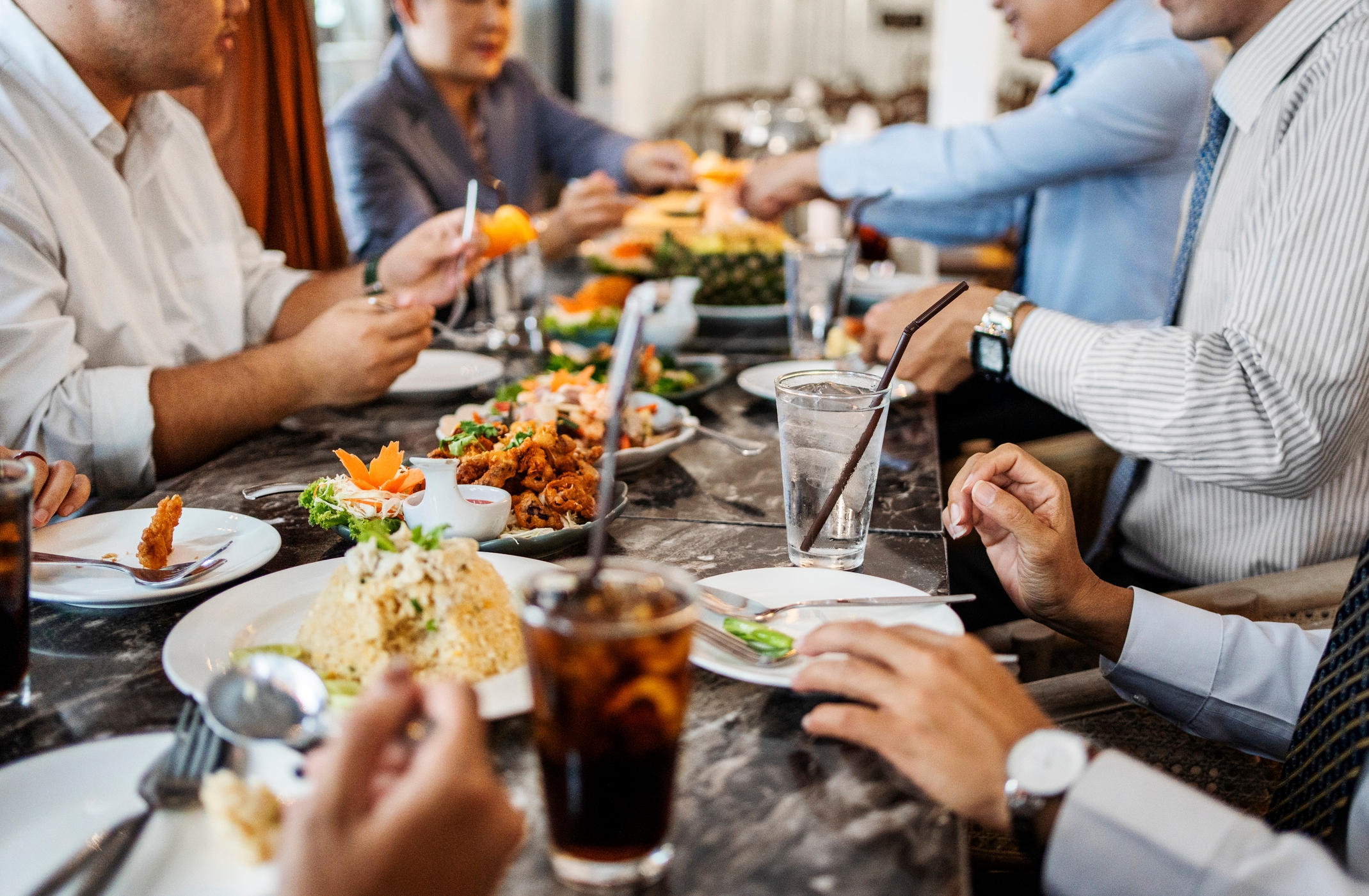 People dining at a table, enjoying various dishes and drinks, engaged in conversation