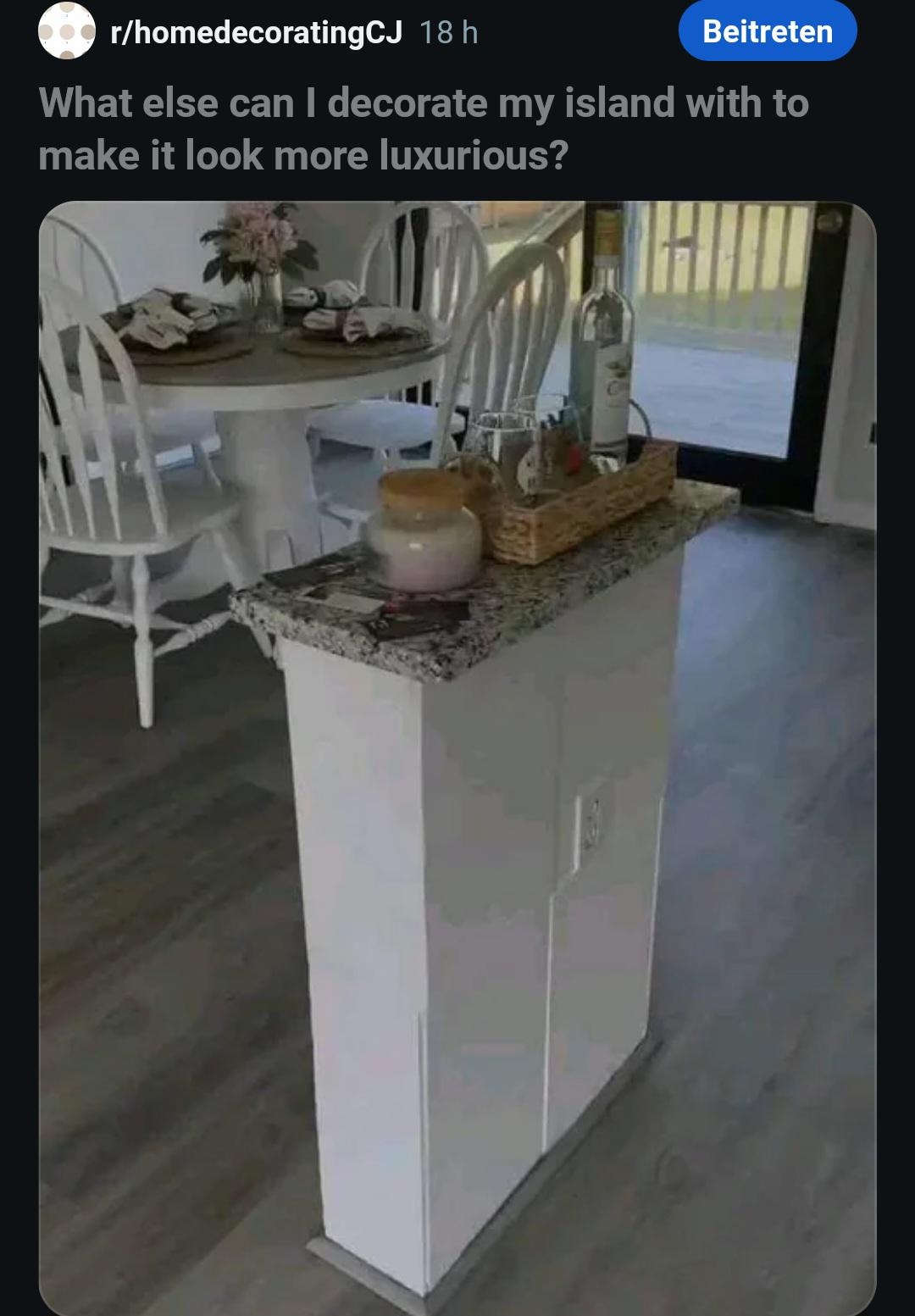 Kitchen island with a granite top and decorative items. Dining table and chairs visible in the background