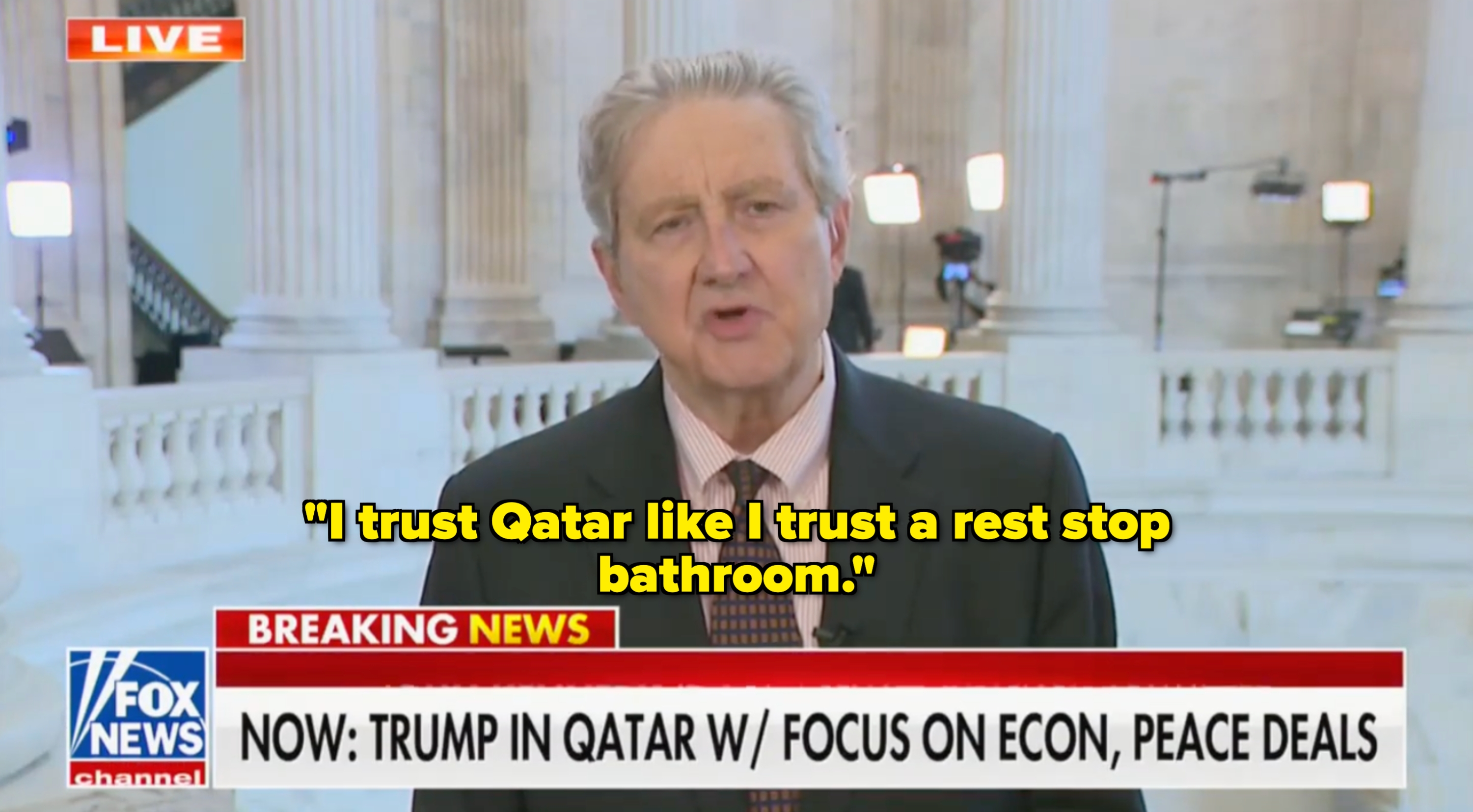 A person in a suit is speaking on a news channel about Trump's visit to Qatar, focusing on economic and peace deals