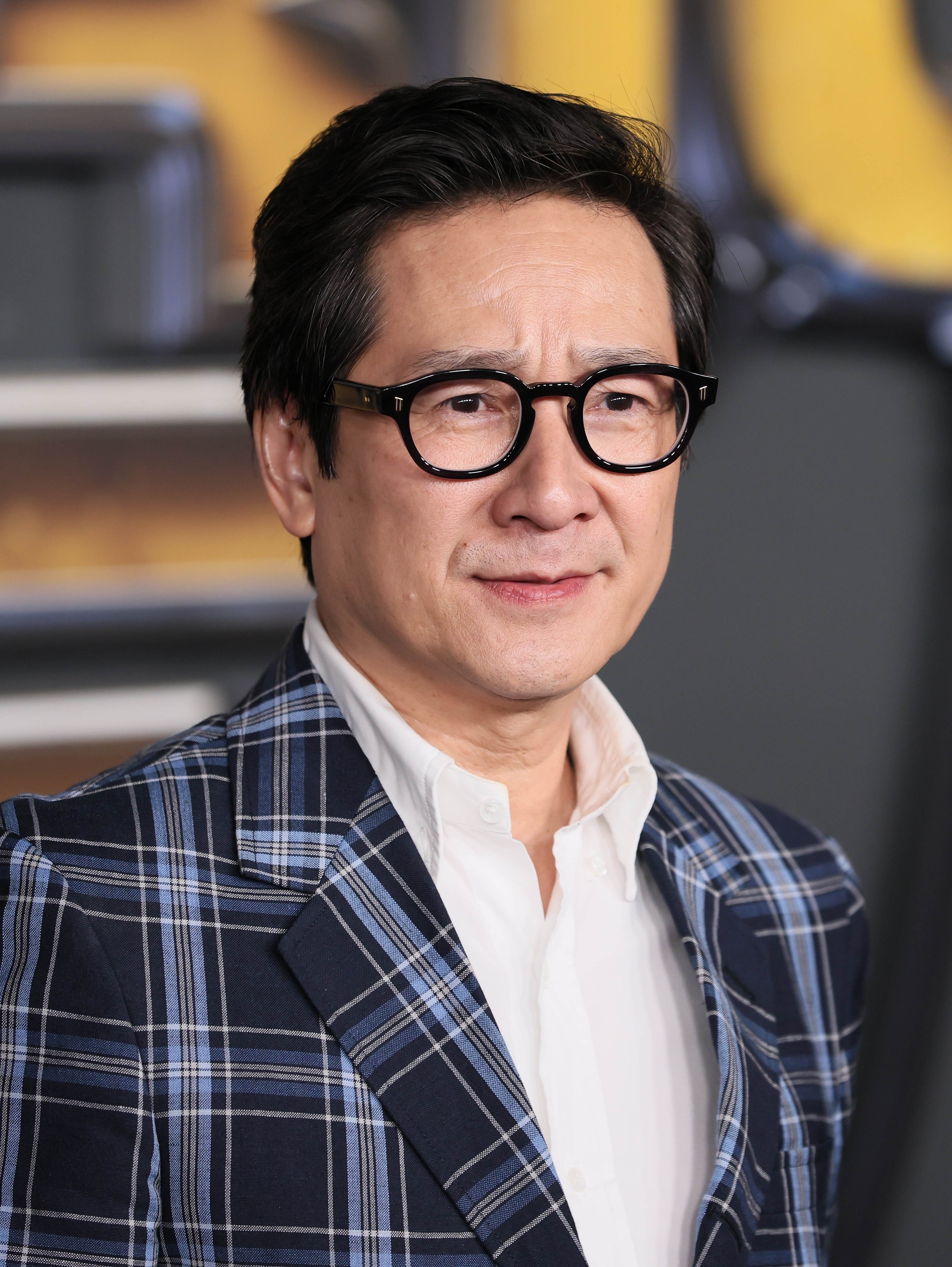 Ke Huy Quan wearing a plaid blazer and glasses, attending a formal event