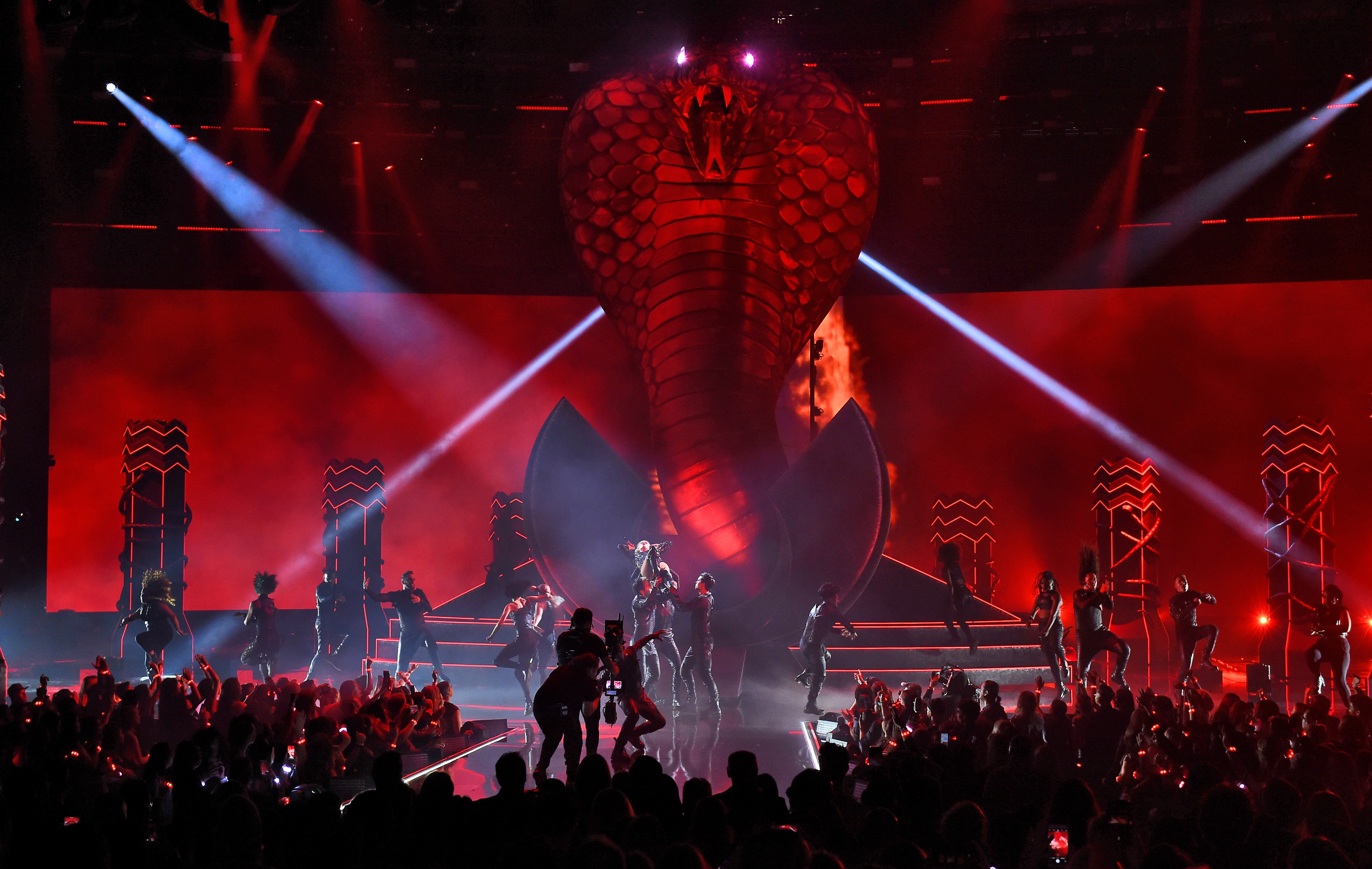 Stage with a giant cobra backdrop during a dynamic concert, surrounded by dancers and dramatic lighting effects
