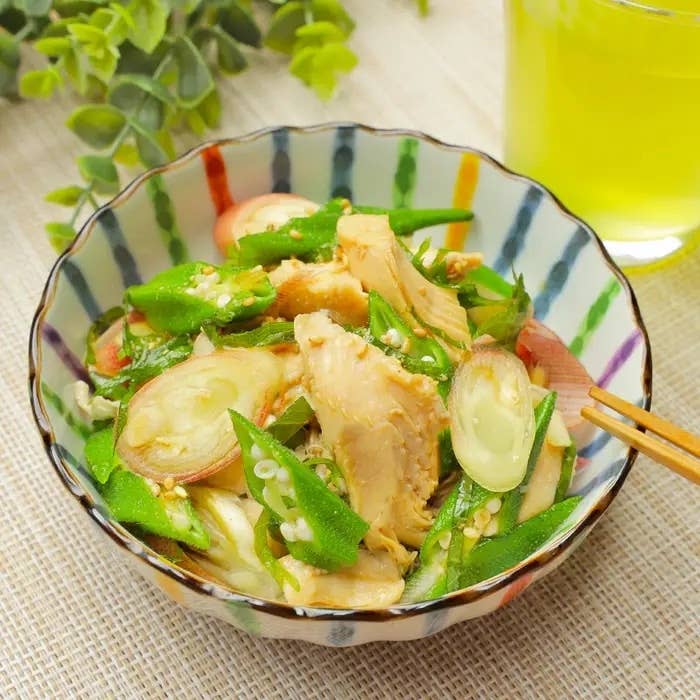 サラダボウルに盛られたスライスされたオクラ、ささみ、玉ねぎの料理。横に黄緑色の飲み物。