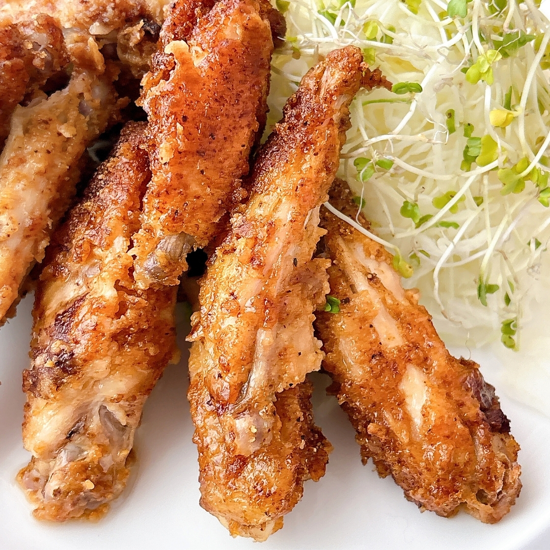 揚げたチキンウィングが一皿に盛られ、隣に細切りキャベツのサラダが添えられています。